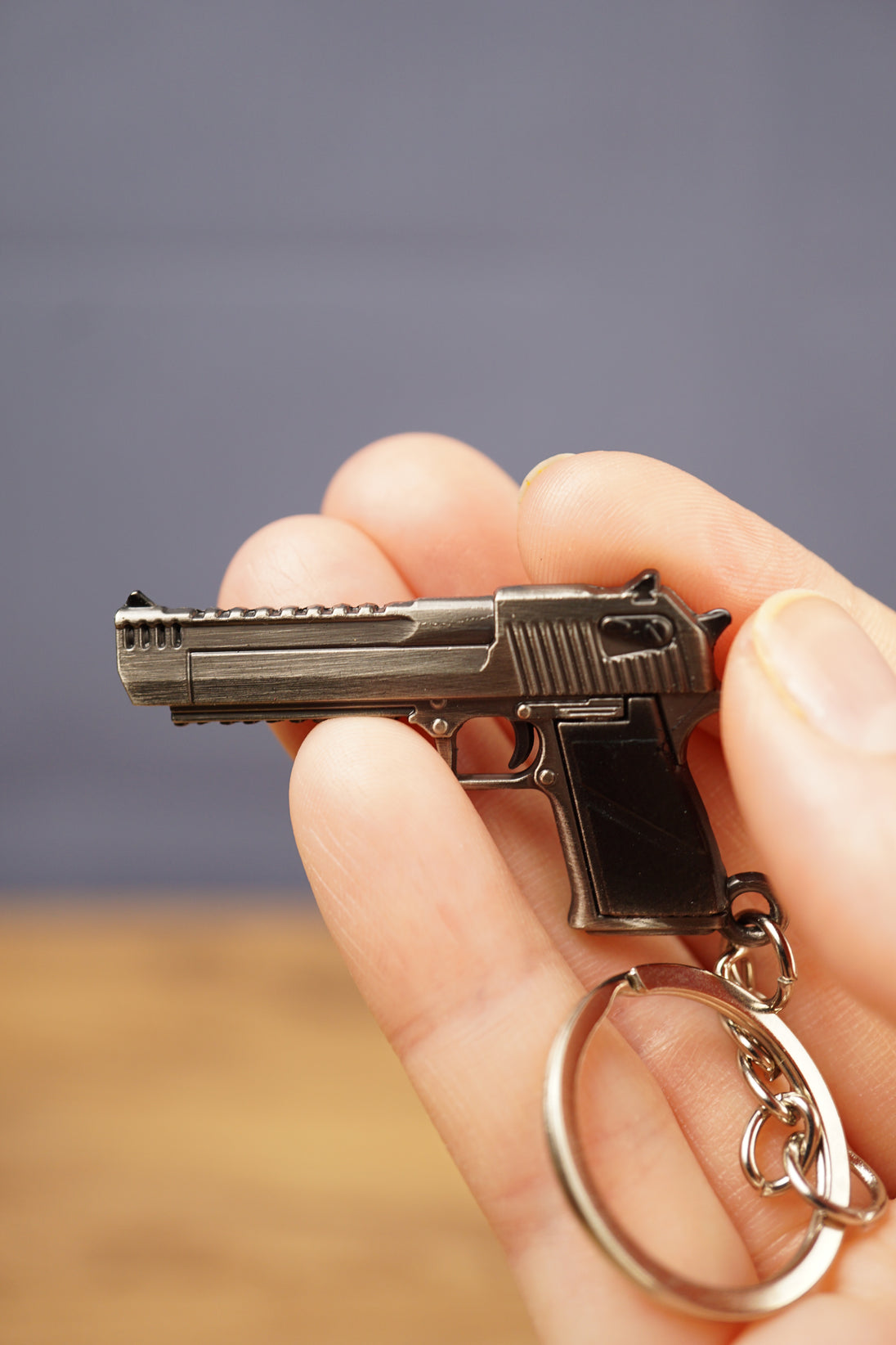 Detailed gamer pistol keyring held in hand with silver keyring loop attached, ideal as an FPS gaming gift or collectible accessory