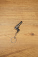 Desert Eagle-style gamer gun keyring on a wood background, angled to show the compact pistol shape, chain link and round keyring loop