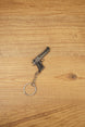 Desert Eagle-style gamer gun keyring on a wood background, angled to show the compact pistol shape, chain link and round keyring loop