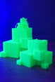 Glow in the dark Subnautica ion cube replicas under blue lighting, showing bright green sci-fi cube collectibles on a tabletop.