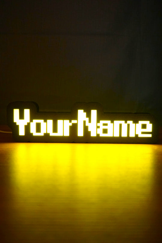 Illuminated YourName LED name sign glowing bright yellow in a dark room with a nostalgic RuneScape-style font design.
