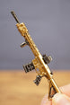 Gold tactical rifle keyring resting in hand with metal key loop, designed as a collectible FPS gamer accessory.