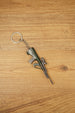 Close-up angled view of AUG-style bullpup gun keychain with detailed magazine, optic and metal keyring chain on wood surface