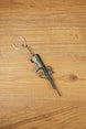 Close-up angled view of AUG-style bullpup gun keychain with detailed magazine, optic and metal keyring chain on wood surface