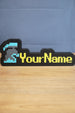 Custom RuneScape-style group ironman nameplate with a blue and grey helmet icon, yellow lettering, and black frame displayed on a wooden tabletop.