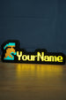 Lit group ironman nameplate with blue and grey helmet icon, bright yellow RuneScape-style lettering, and a soft glow on the desk surface.