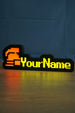 Glowing hardcore ironman desk sign with a red helmet icon, bright yellow personalized text, and warm reflection across the desk surface.