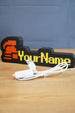 Hardcore ironman RuneScape-inspired nameplate shown with USB cable, red helmet icon, yellow lettering, and black casing on a wooden surface