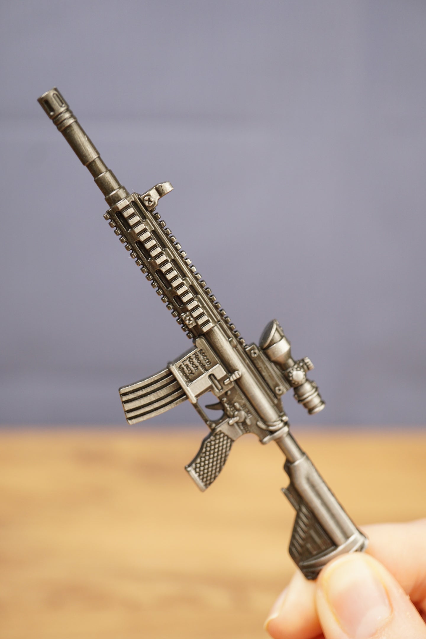 Close-up HK 416A5 rifle keychain replica held in hand showing miniature scale, detailed rail, optic, stock and metal alloy finish