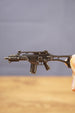 Close-up of HK G36 metal rifle keyring held between fingers, showing miniature tactical details and keychain size