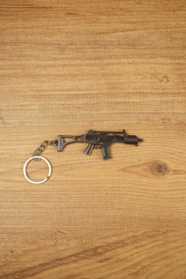 HK G36 metal rifle keyring laid flat on a wood surface, detailed tactical FPS gamer keychain with silver ring and chain