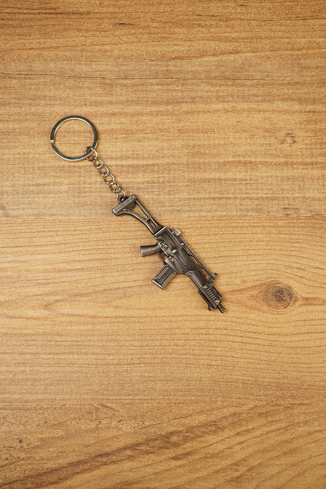 HK G36 rifle keyring angled on a wooden tabletop, compact metal gamer keychain for tactical shooter and FPS fans