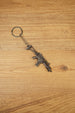 HK G36 rifle keyring angled on a wooden tabletop, compact metal gamer keychain for tactical shooter and FPS fans