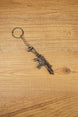 HK G36 rifle keyring angled on a wooden tabletop, compact metal gamer keychain for tactical shooter and FPS fans