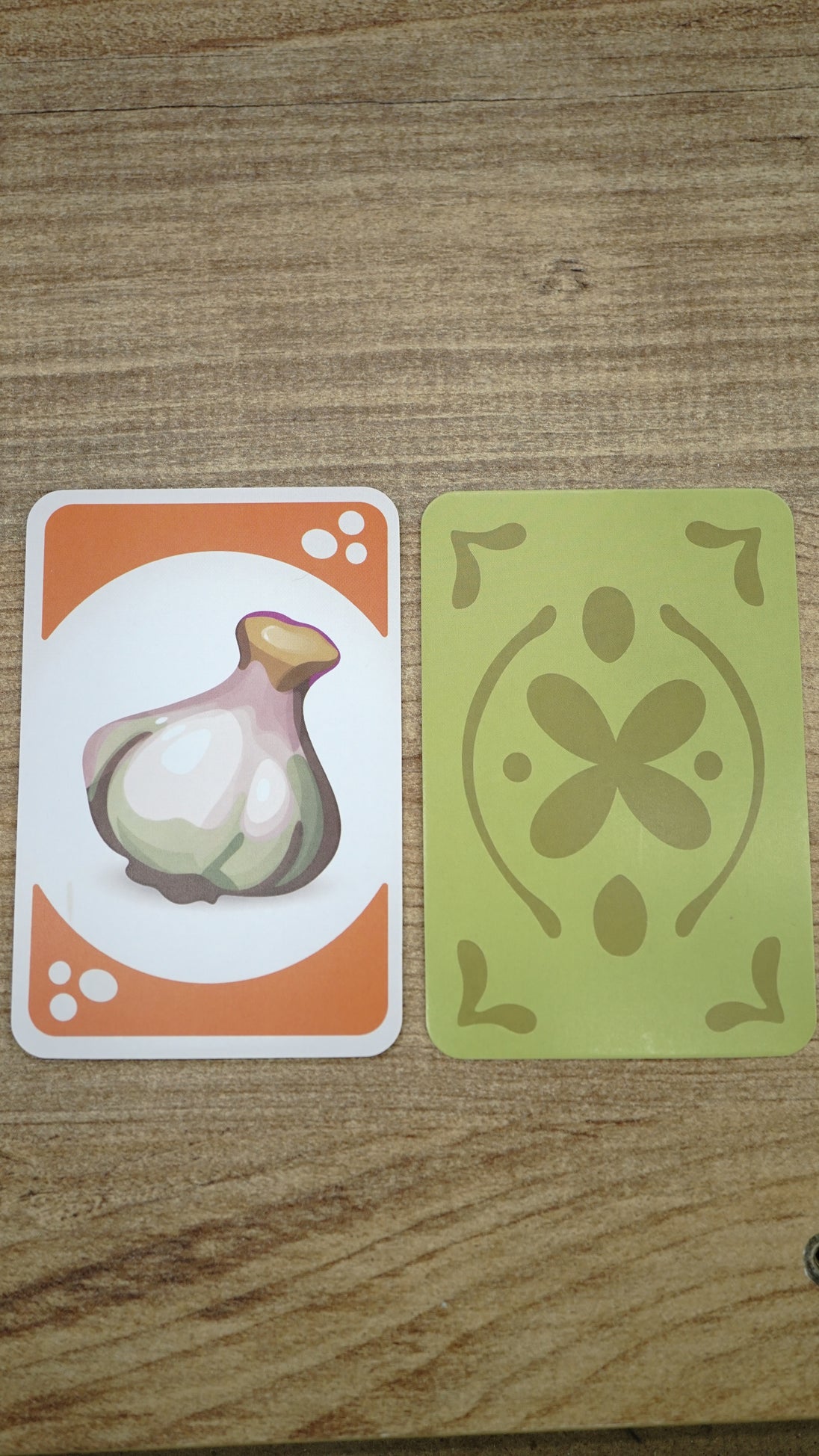 Front and back view of a Hotpot playing card showing an illustrated garlic ingredient card beside the decorative green card-back design.