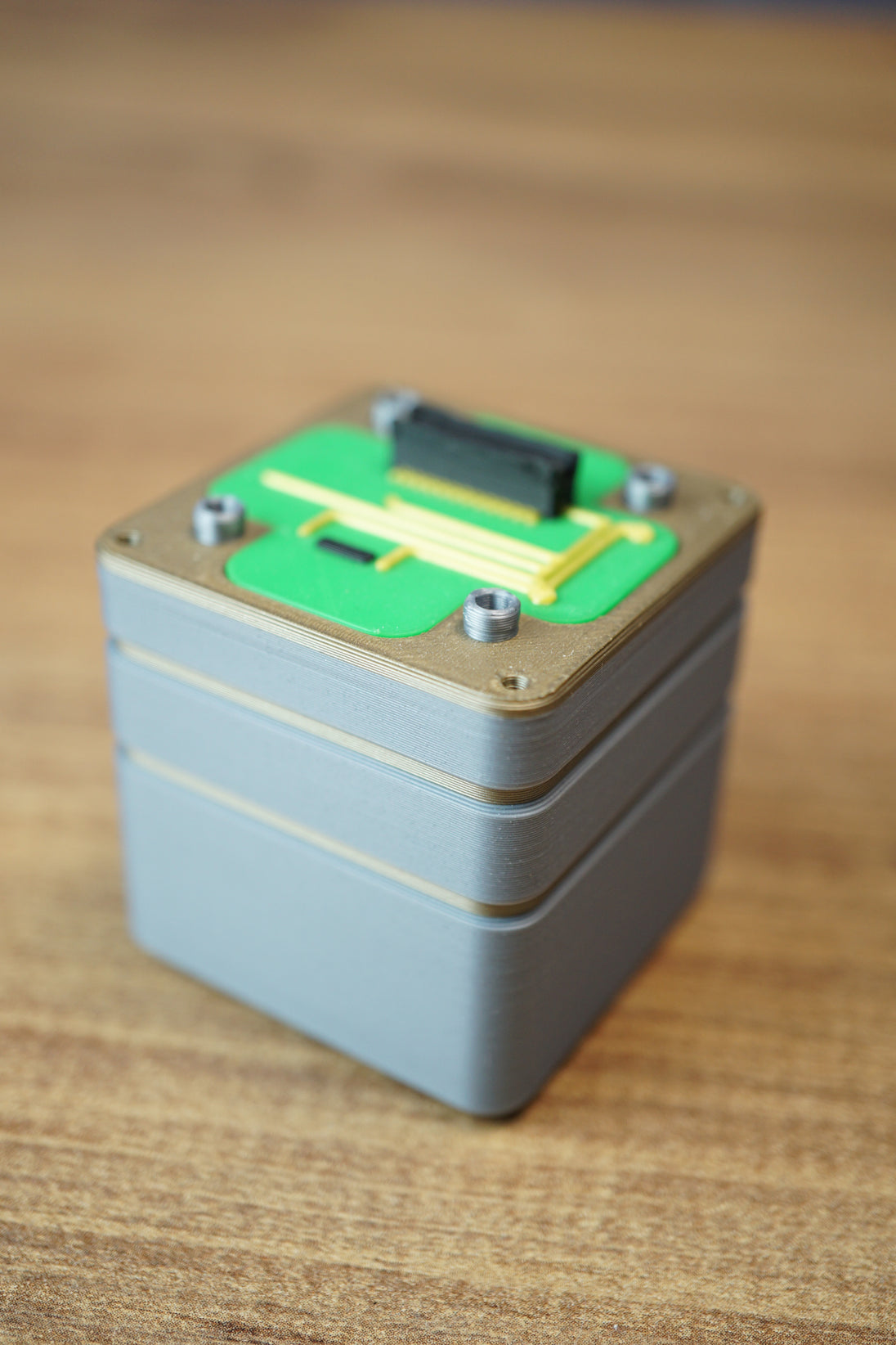 Close-up product view of an Iridium thermal vision module replica with grey casing, green circuit-style top, and raised connector details.