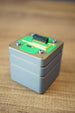Close-up product view of an Iridium thermal vision module replica with grey casing, green circuit-style top, and raised connector details.