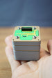 Compact Iridium thermal vision module replica displayed in hand, featuring grey layered casing, green circuit board design, and detailed top connector.