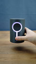 Hand holding the 12cm Knowledge Stone RGB lamp for scale, with the circular LED ring and vertical light strip illuminated pale purple.