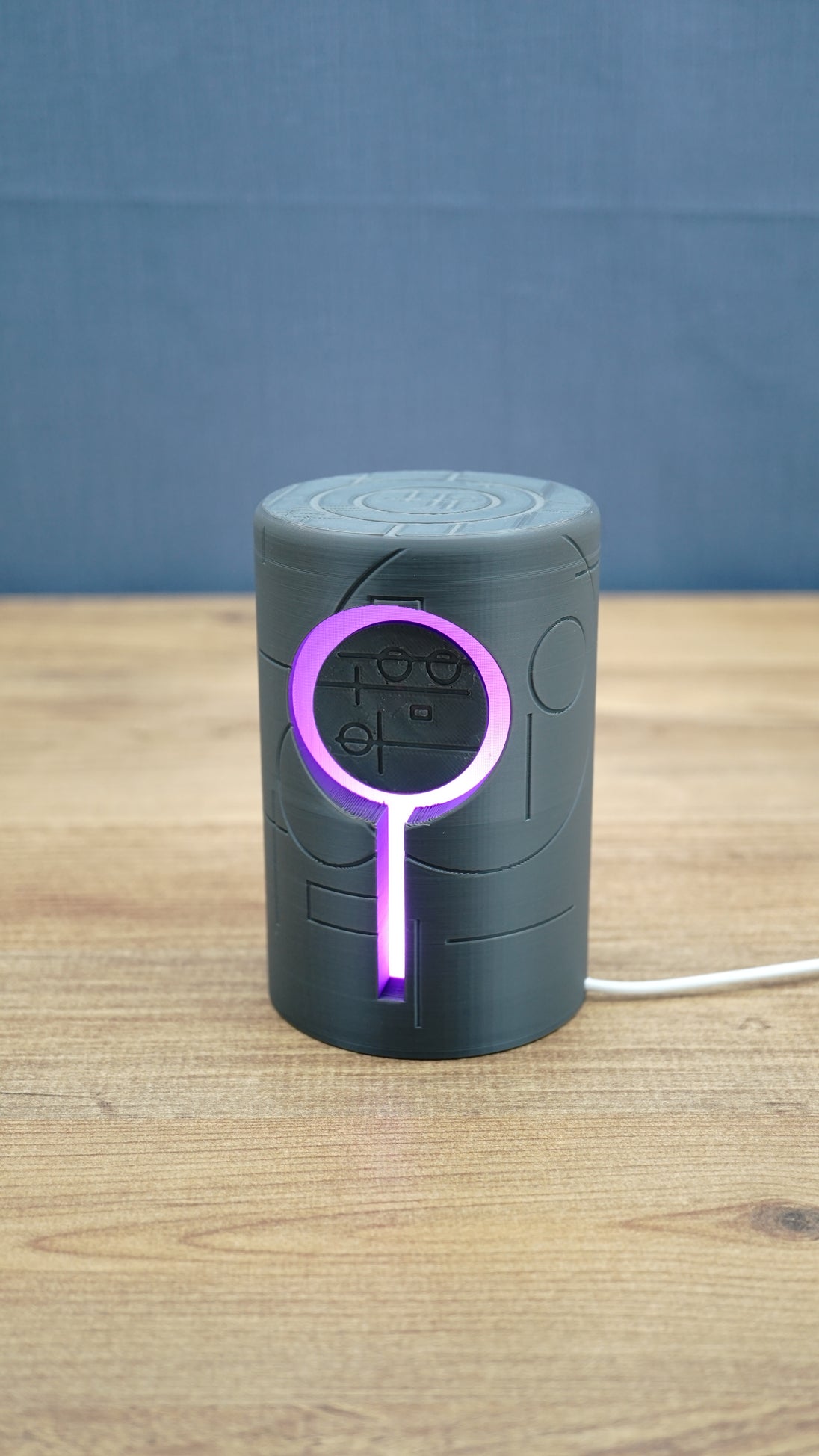 Knowledge Stone RGB LED gaming light illuminated purple around the circular centre and vertical light channel on a dark grey sci-fi body.