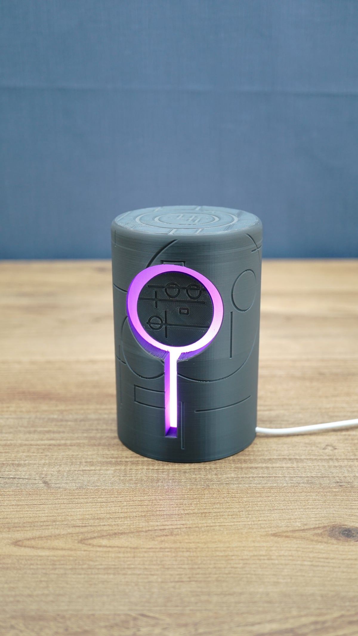 Knowledge Stone RGB LED gaming light illuminated purple around the circular centre and vertical light channel on a dark grey sci-fi body.
