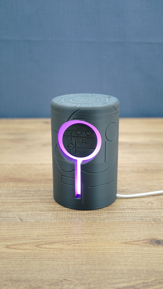 Knowledge Stone RGB LED gaming light illuminated purple around the circular centre and vertical light channel on a dark grey sci-fi body.