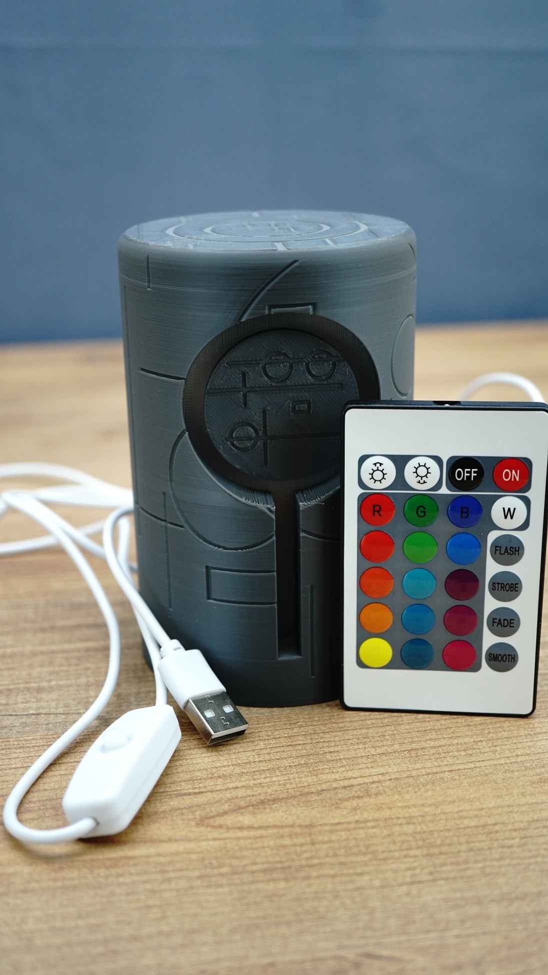 Knowledge Stone USB LED lamp displayed with its colour remote controller, USB cable and inline power switch on a wooden gaming desk.