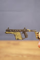 Close-up KRISS Vector style miniature SMG keychain held by hand, showing detailed rail, grip and tactical olive green body finish
