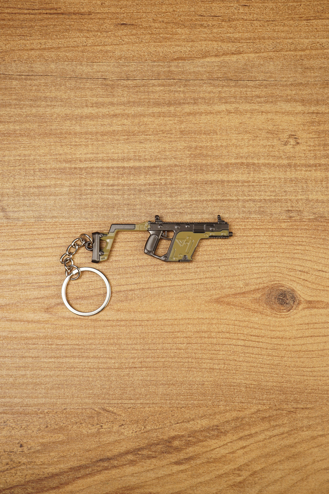 KRISS Vector Gen 2 SMG keychain lying flat on a wooden surface with metal keyring attached, ideal tactical gaming gift for FPS fans