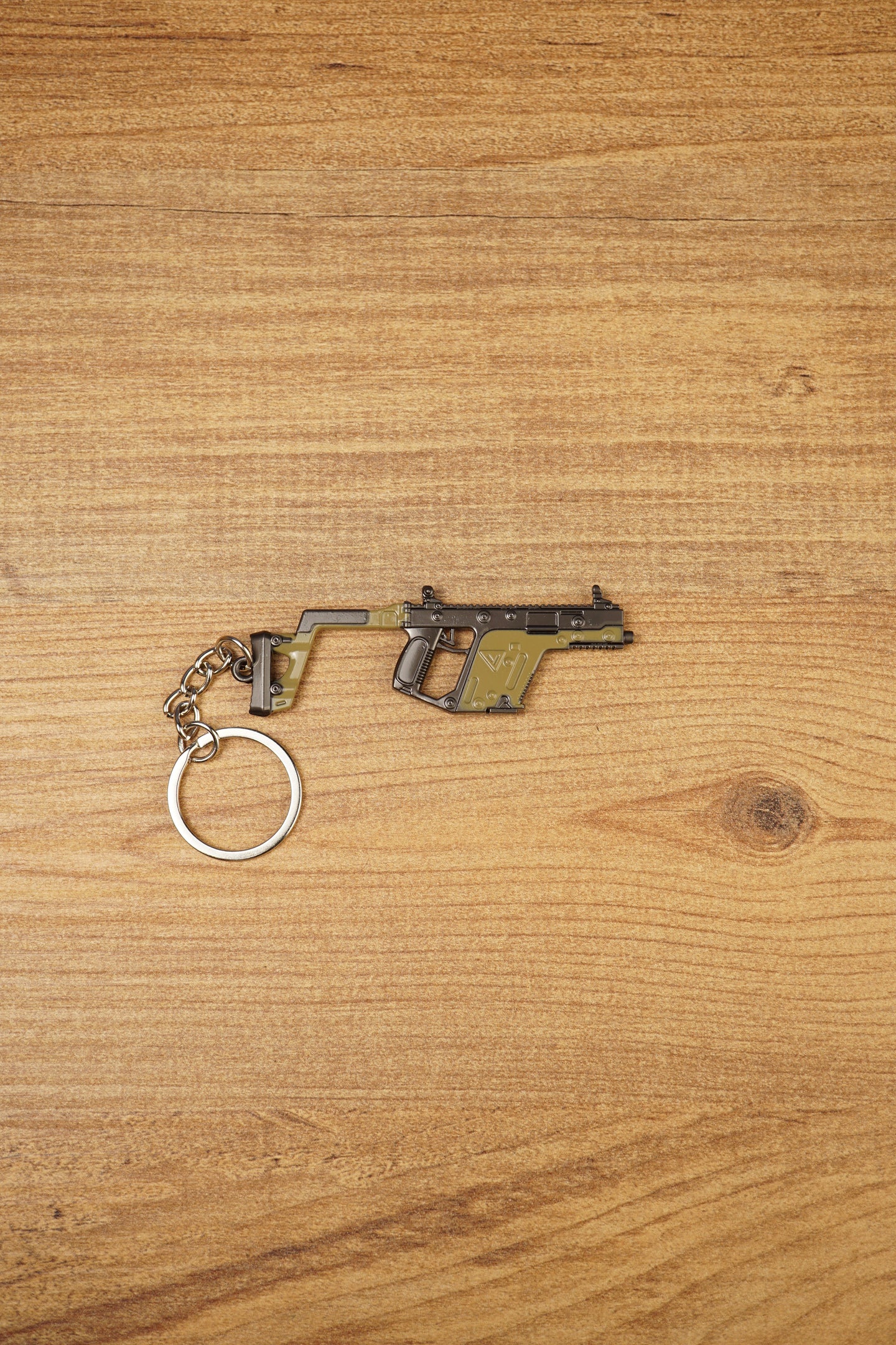 KRISS Vector Gen 2 SMG keychain lying flat on a wooden surface with metal keyring attached, ideal tactical gaming gift for FPS fans