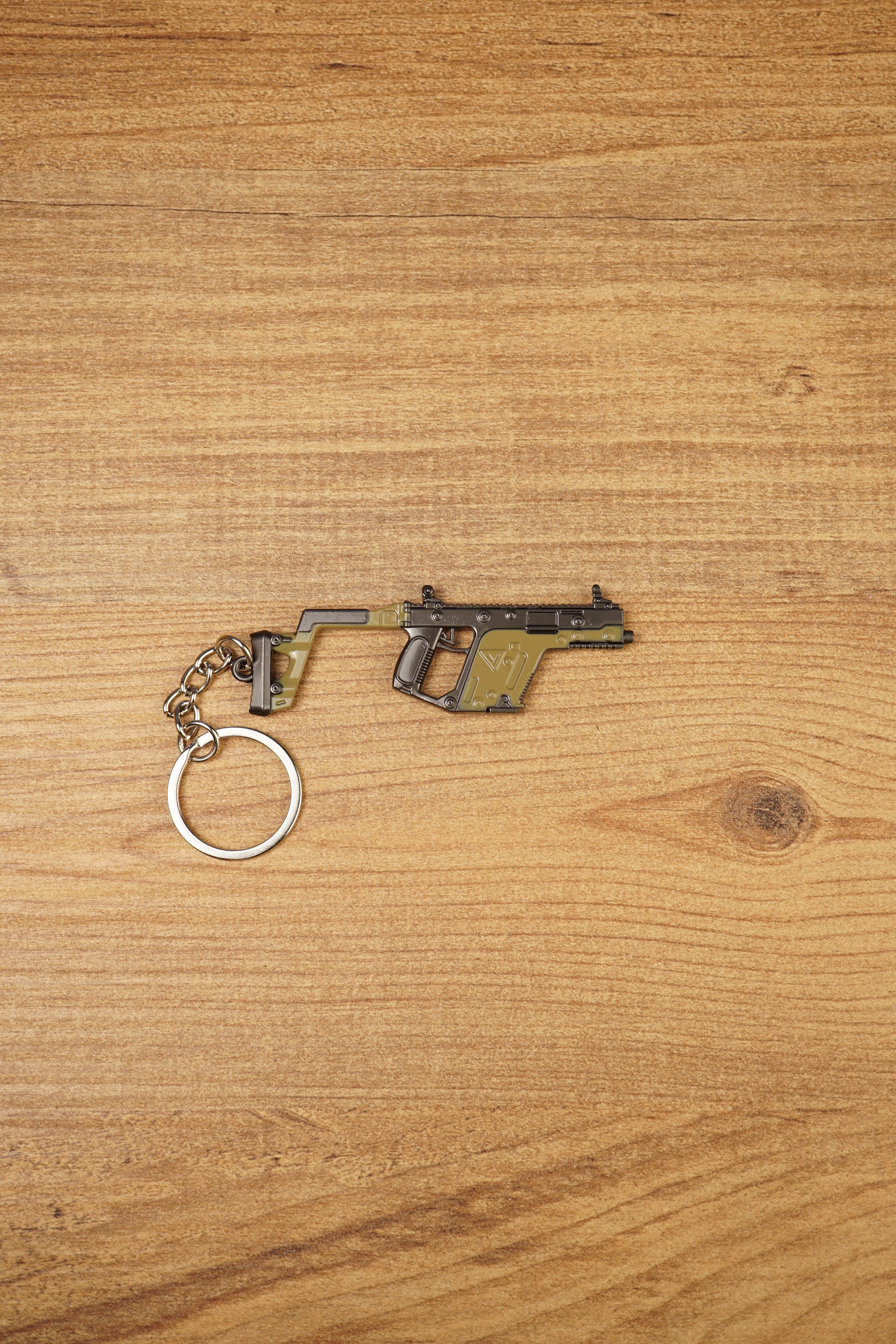 KRISS Vector Gen 2 SMG keychain lying flat on a wooden surface with metal keyring attached, ideal tactical gaming gift for FPS fans