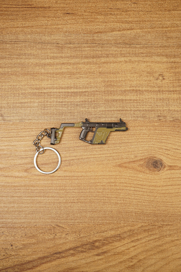 KRISS Vector Gen 2 SMG keychain lying flat on a wooden surface with metal keyring attached, ideal tactical gaming gift for FPS fans