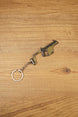 Angled KRISS Vector style SMG keyring on wood showing olive green and black details, a compact collectible for tactical shooter gamers