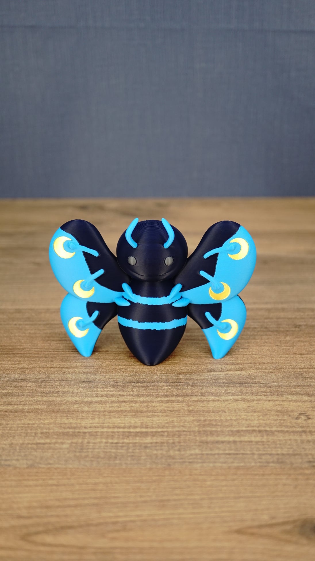 Front view of the large Duskwing Butterfly figure with a dark-blue body, curved blue antennae and patterned blue-and-gold wings.