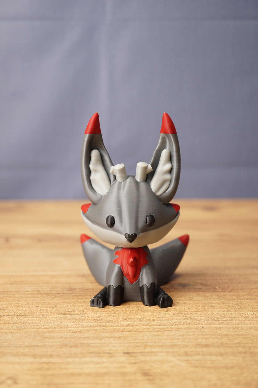 Large Obsidian Kitsuu fox figure front view with grey colouring, red chest accent, black paws and tall pointed ears