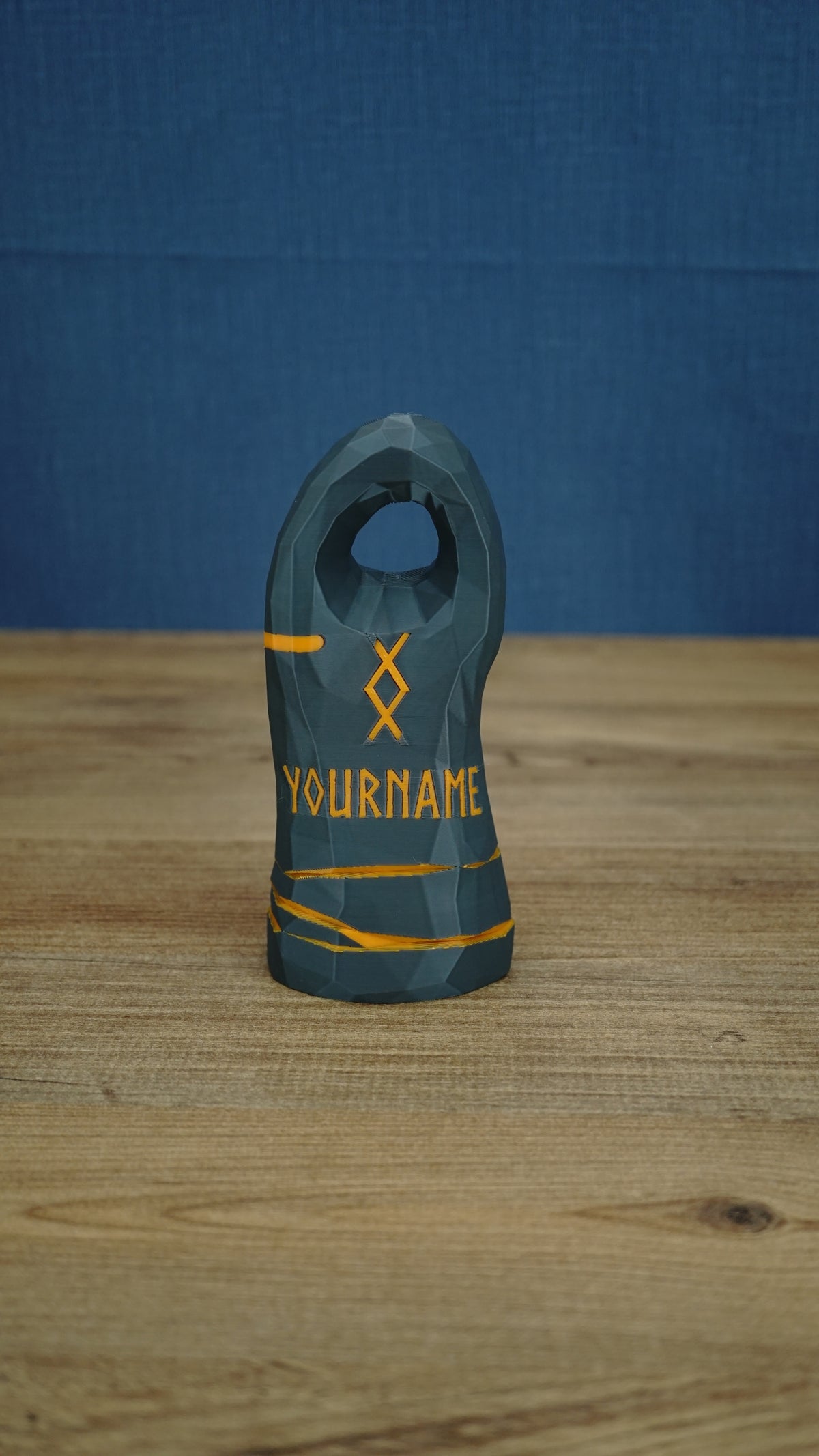 Large dark gray Valheim-inspired tombstone with a circular top cutout, orange rune symbol, YOURNAME text, and painted orange band details.