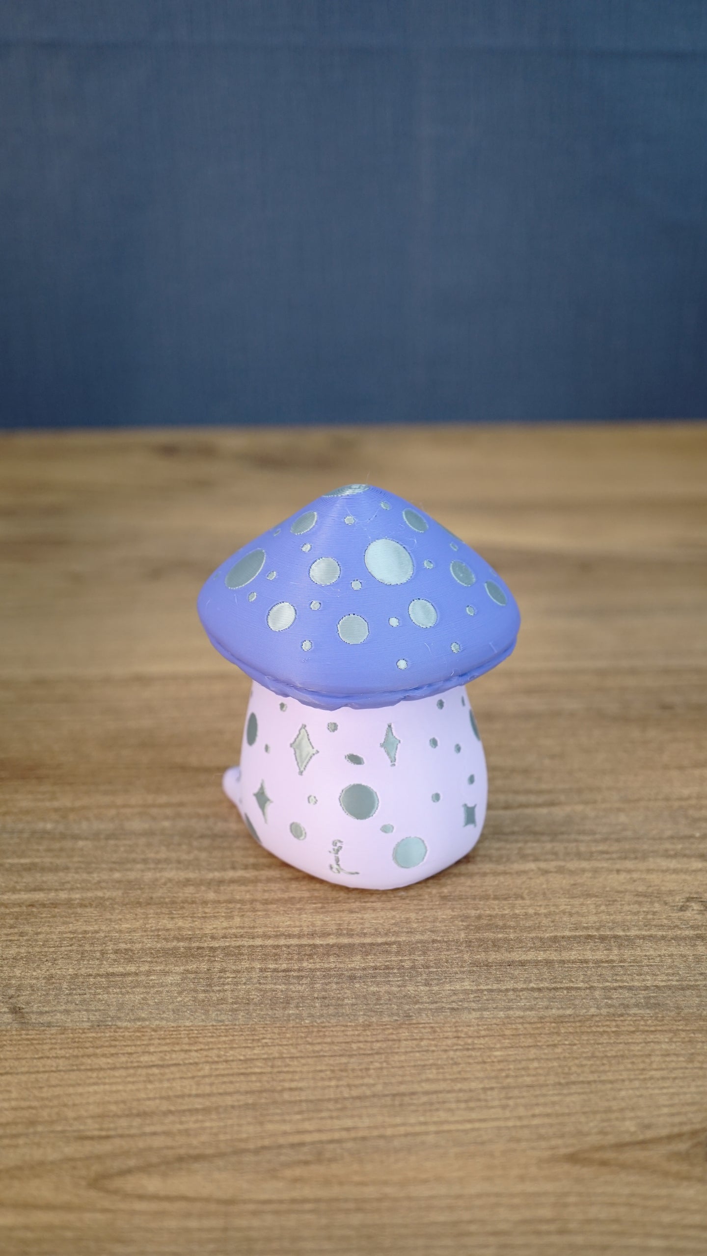 Back view of the Madrinas Fun Guy figurine showing silver spots and star markings on its pale pink body beneath a lavender cap.