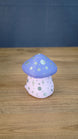 Back view of the Madrinas Fun Guy figurine showing silver spots and star markings on its pale pink body beneath a lavender cap.