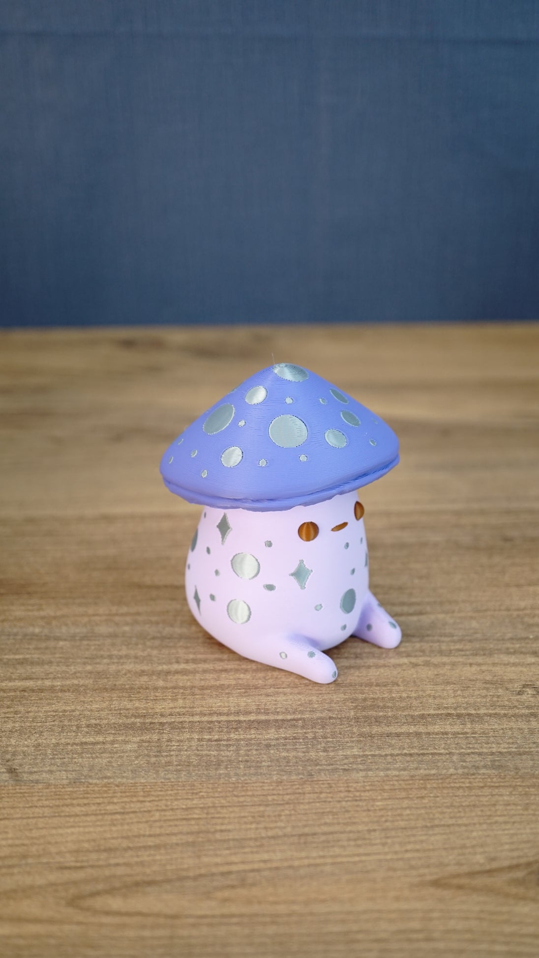 Side view of the Madrinas Fun Guy figurine showing its lavender cap, silver spots, pale pink body, and small rounded feet.