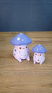 Large and small Madrinas Fun Guy figurines with purple mushroom caps, silver spots, and pastel pink bodies.