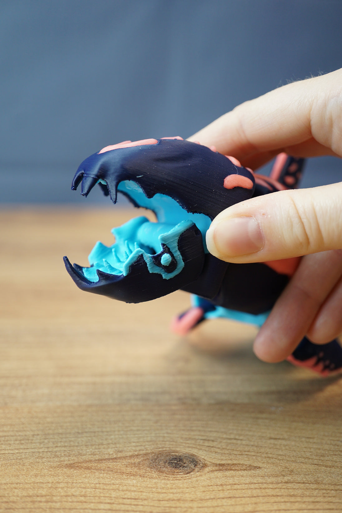 Close-up of Marrowbreach creature figure with articulated open mouth, revealing light blue interior, dark outer shell and coral red markings.