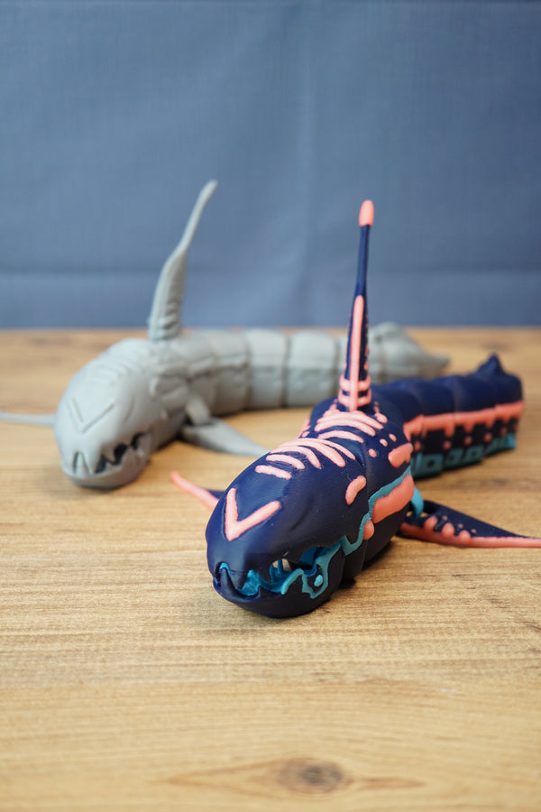 Marrowbreach inspired creature figure displayed with grey prototype figure in background, showing poseable fins, body segments and alien sea creature shape.