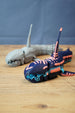 Angled front view of Marrowbreach inspired collectible figure with dark blue body, coral red markings, light blue jaw detail and segmented tail.