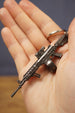 Mini AK-12 rifle keyring resting in hand with dark metal finish, durable chain and realistic tactical accessory details