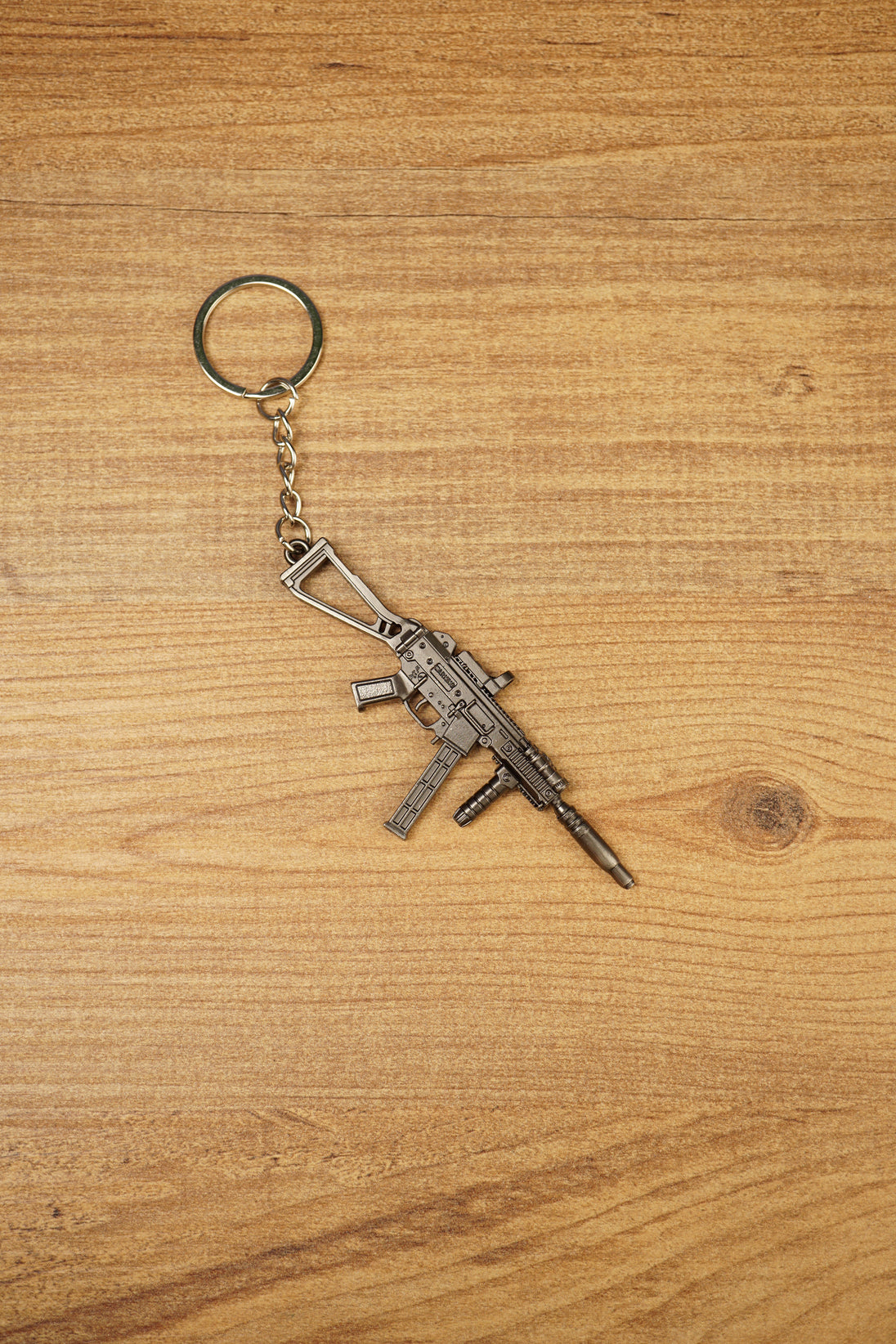 UMP45-style SMG keyring on a wood background with visible folding stock, extended magazine and tactical shooter collectible details