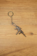 UMP45-style SMG keyring on a wood background with visible folding stock, extended magazine and tactical shooter collectible details