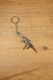 UMP45-style SMG keyring on a wood background with visible folding stock, extended magazine and tactical shooter collectible details