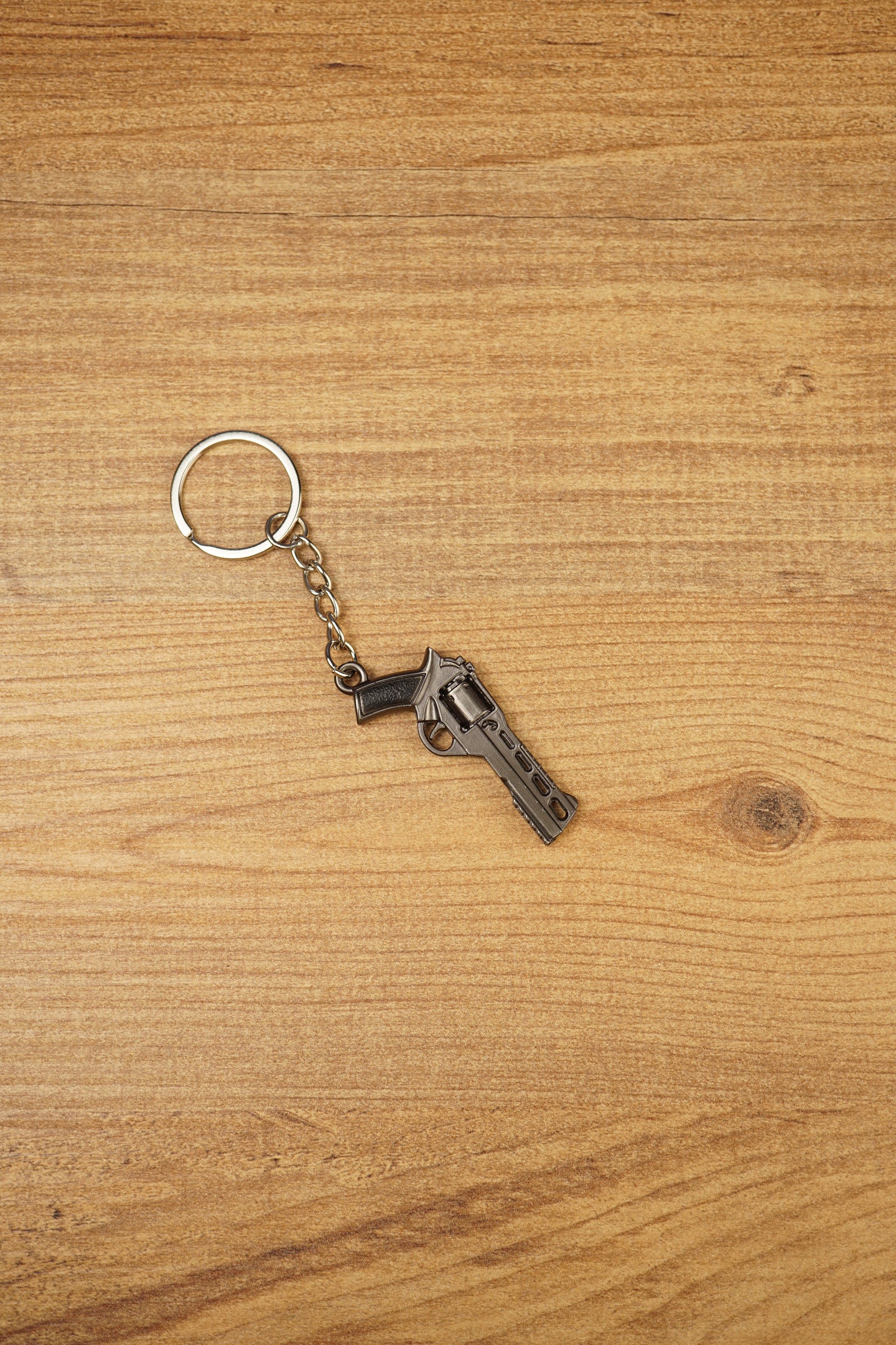Miniature Rhino-style .357 revolver keyring with chain and silver ring, displayed on wood as a collectible FPS game accessory