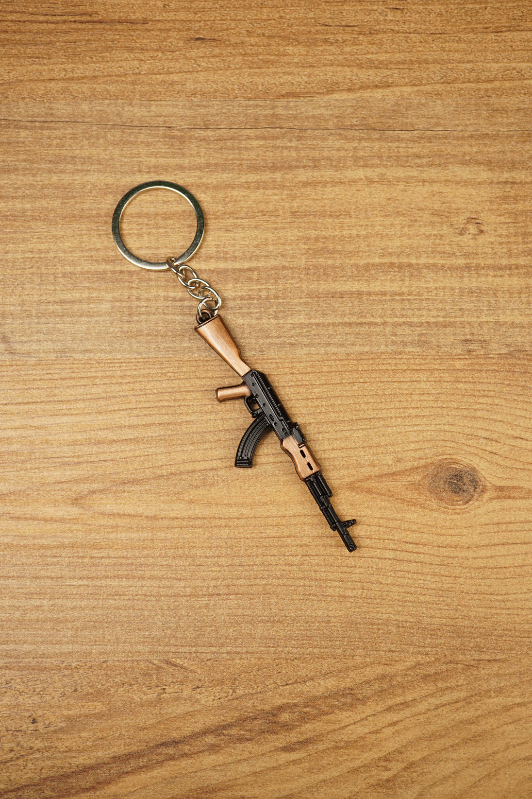AK-74 style rifle keychain with metal ring and chain on wooden table, tactical gaming accessory for FPS and shooter fans