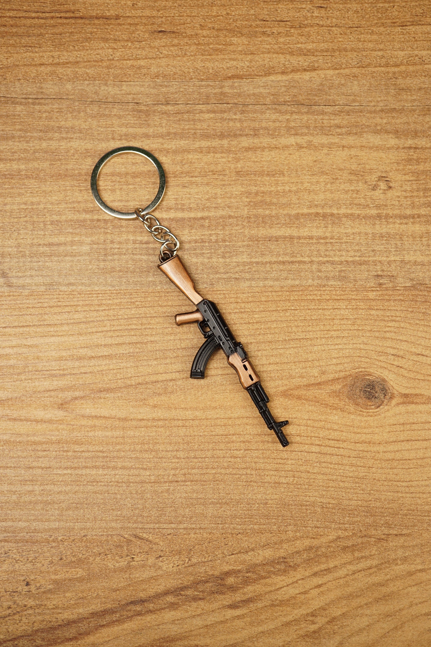 AK-74 style rifle keychain with metal ring and chain on wooden table, tactical gaming accessory for FPS and shooter fans